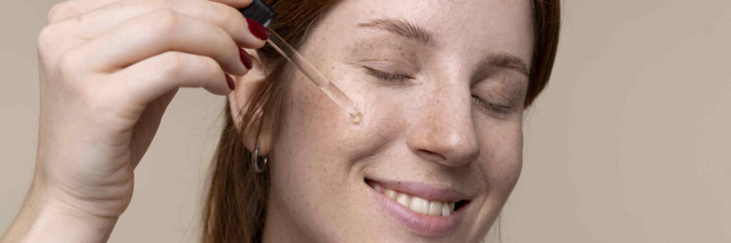 Mujer aplicando sérum facial con gotero, cuidando e hidratando su piel