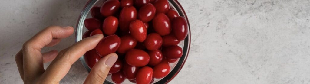 Mano tomando arándanos de un recipiente, destacando sus propiedades medicinales y beneficios antioxidantes.