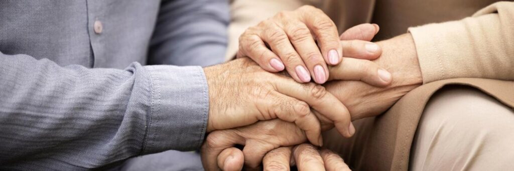 Manos entrelazadas de personas mayores, simbolizando apoyo y cuidado para fortalecer el sistema inmune.