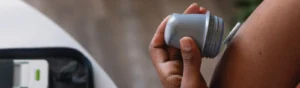Primer plano de una persona aplicando un sensor de monitoreo de glucosa en la parte superior de su brazo con un dispositivo especial.