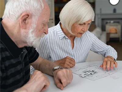 Dos personas mayores de edad comparten un rompecabezas.