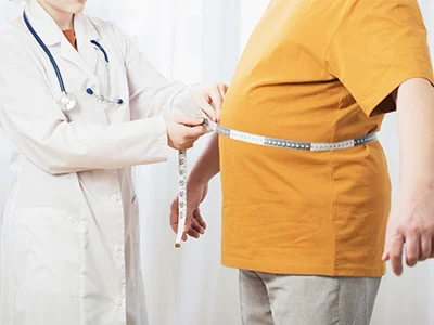 Una doctora mide la circunferencia abdominal de su paciente con una cinta métrica.