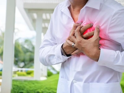 Hombre tomándose el pecho con expresión de dolor, indicando síntomas de un posible ataque al corazón o afección cardíaca.