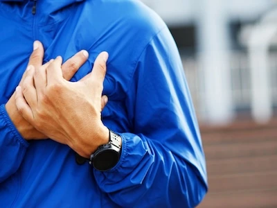 Persona tocándose el pecho por dolor, posible síntoma de problemas cardíacos.