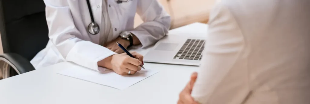 Médico tomando notas durante una consulta médica con paciente
