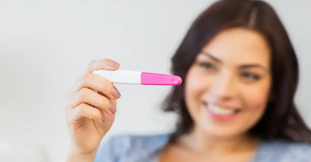 Mujer sosteniendo una prueba de embarazo mientras sonrie, haciendo referencia a la fertilidad femenina