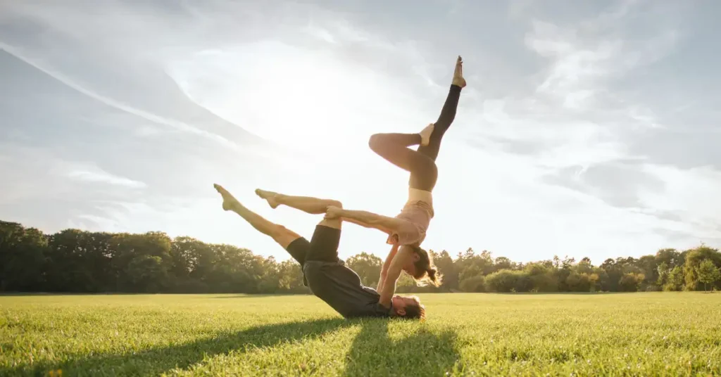 Hombre y mujer haciendo yoga en el cesped, haciendo referencia a vitaminas y suplementos para fortalecer el sistema inmune
