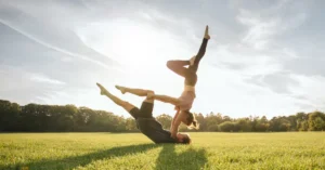 Hombre y mujer haciendo yoga en el cesped, haciendo referencia a vitaminas y suplementos para fortalecer el sistema inmune