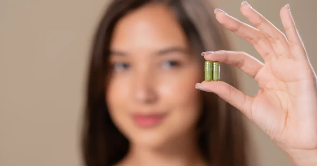 Mujer sosteniendo en primer plano capsulas de suplementos vitaminicos, haciendo referencia a vitaminas y suplementos