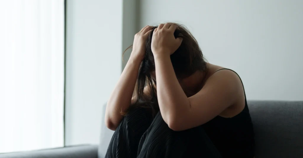 Mujer sentada en el sofá muy estresada con las manos en la cabeza tapandose la cara. haciendo alusión al artículo El vinculo secreto como el estrés afecta tu corazón y tu cuerpo