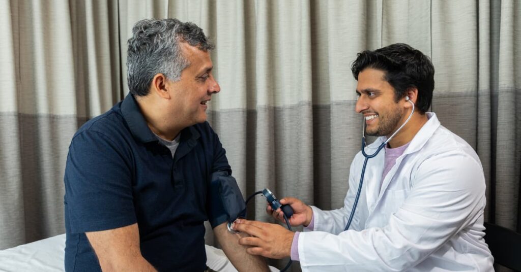 Cardiologó y paciente hablando mientras le miden la tensión, haciendo alusión a los secretos para una salud cardiaca fuerte y duradera
