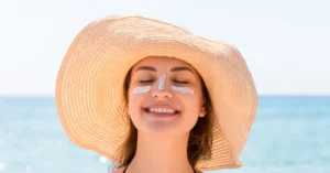Mujer en la plata con protector solar en su cara, haciendo referencia al articulo protector solar definitivo, la defensa inteligente contra la radiación Chilena