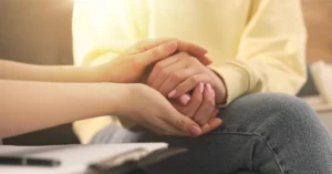 Manos de personas sosteniendo y brindando consuelo y apoyo emocional, haciendo referencia al artículo Apoyo emocional al paciente con cáncer: Guía esencial para acompañar sin abrumar