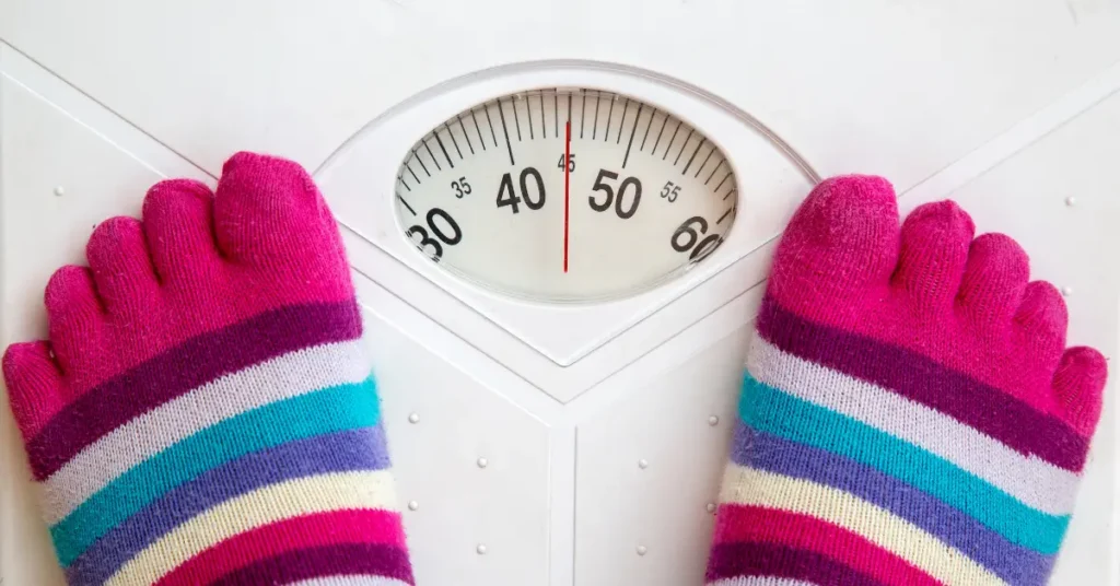 Persona viendo su peso en la vascula Guía indispensable para bajar de peso de forma saludable y sostenible