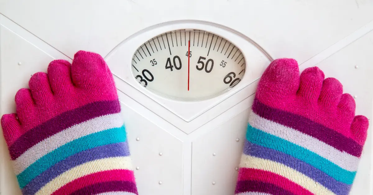 Persona viendo su peso en la vascula Guía indispensable para bajar de peso de forma saludable y sostenible