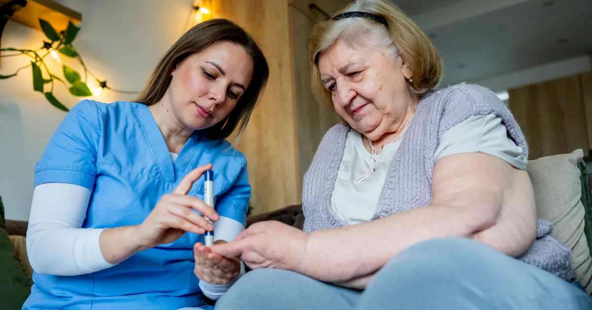 Enfermera profesional realizando una prueba rápida de azúcar a una paciente adulta mayor en casa, paso fundamental en la ruta médica para el diagnóstico de la diabetes.